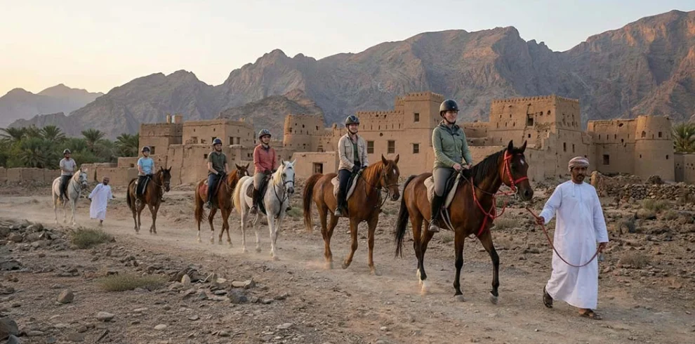 Riders on horseback with a guide below the old houses of Al Hamra