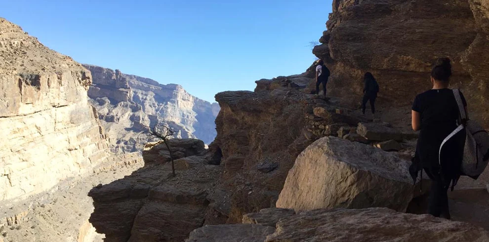 A walker on the rocky rim of the canyon on Jabal Shams