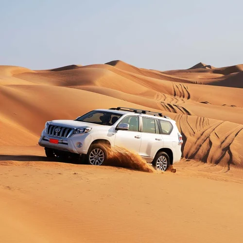A four-wheel drive climbing a sand dune