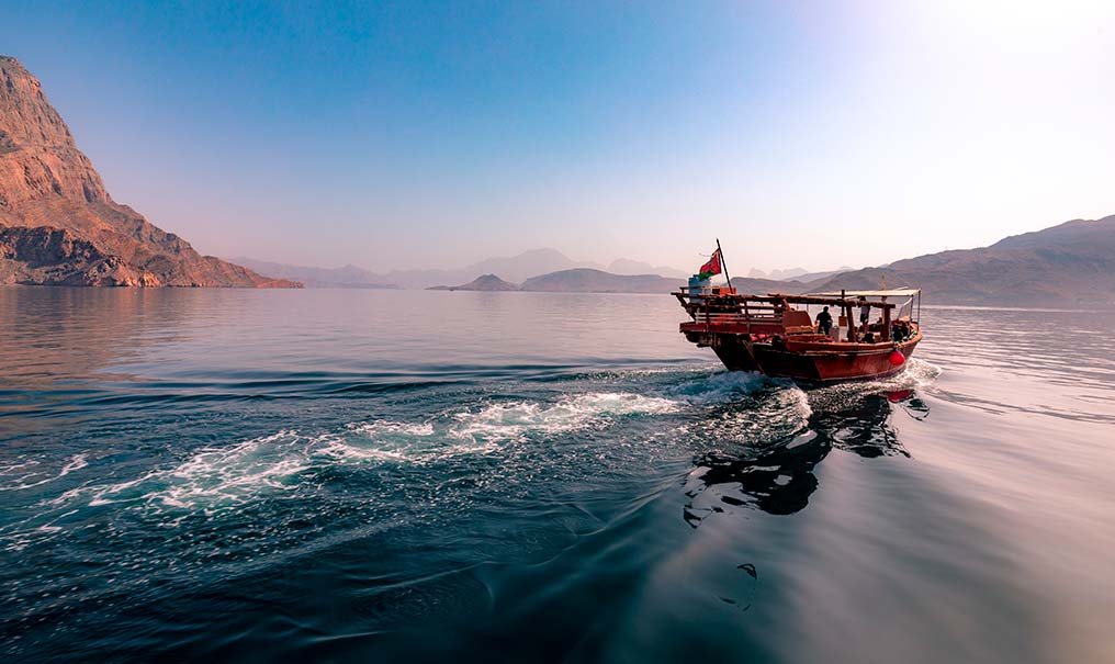 A dhow speeding through a fjord in Musandam