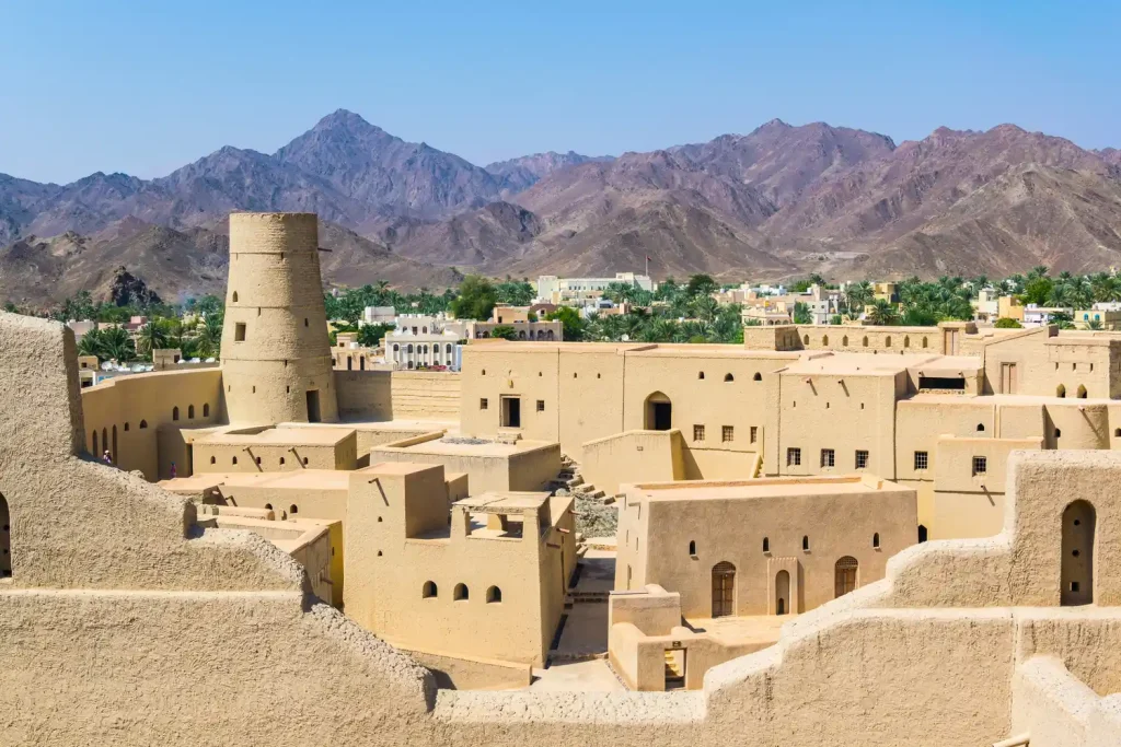 Bahla Fort, a large mud-brick fort with a tower, below the mountains