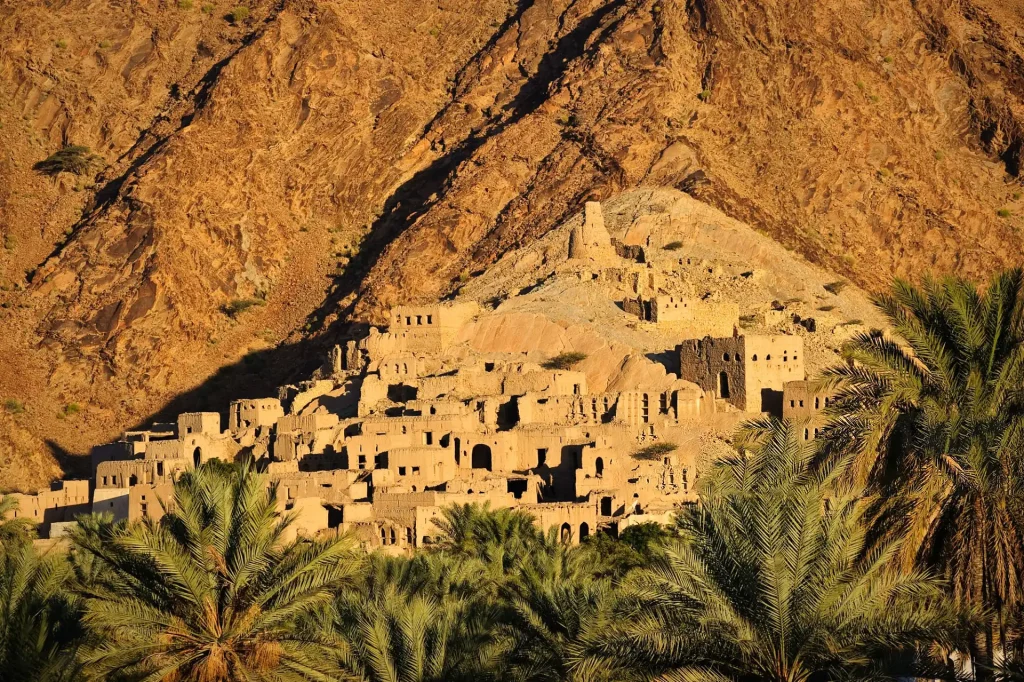 The ruined mud-brick old town of Birkat Al Mouz above palm groves