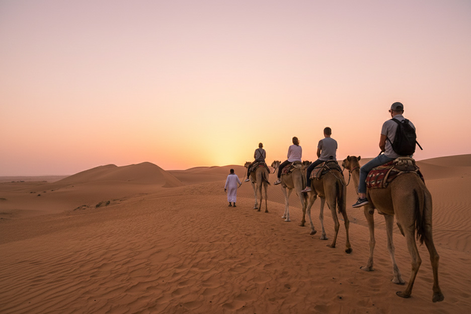 A camel caravan crossing the dunes at sunset