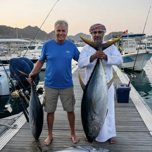 Two anglers on a jetty holding large tuna