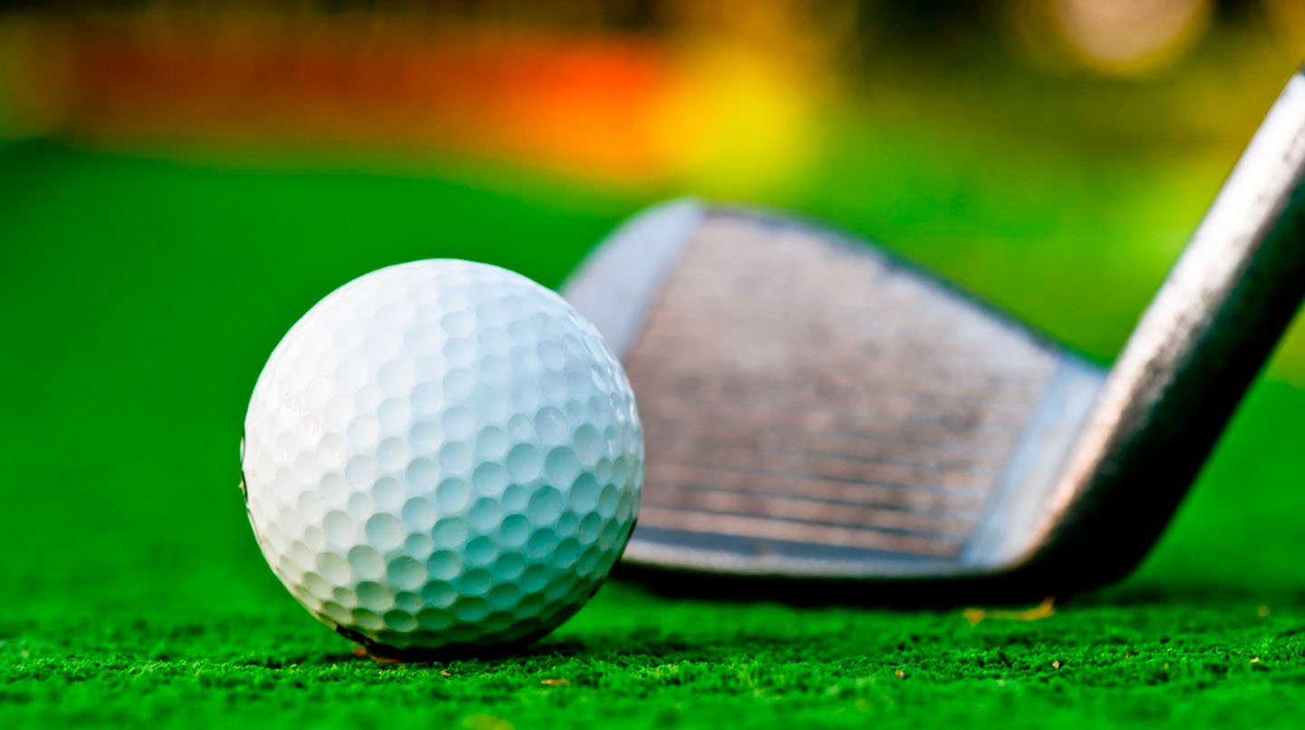 Golf ball resting beside an iron on the green