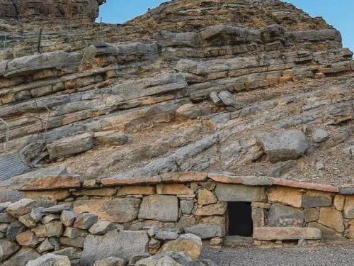 An old stone house below layered rock on Jebel Harim
