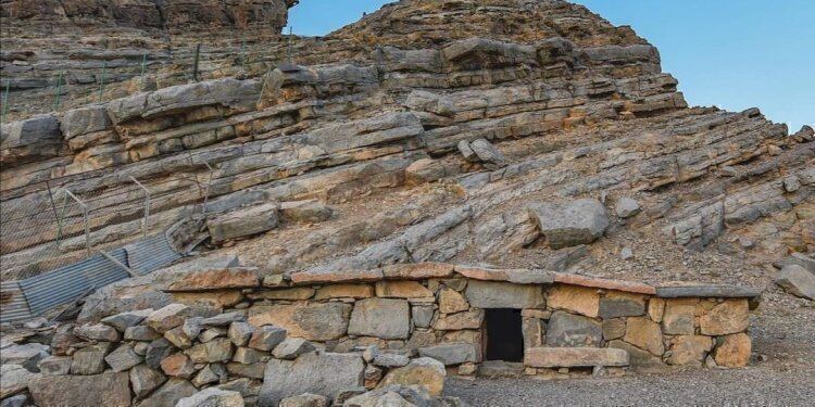 An old stone house below layered rock on Jebel Harim