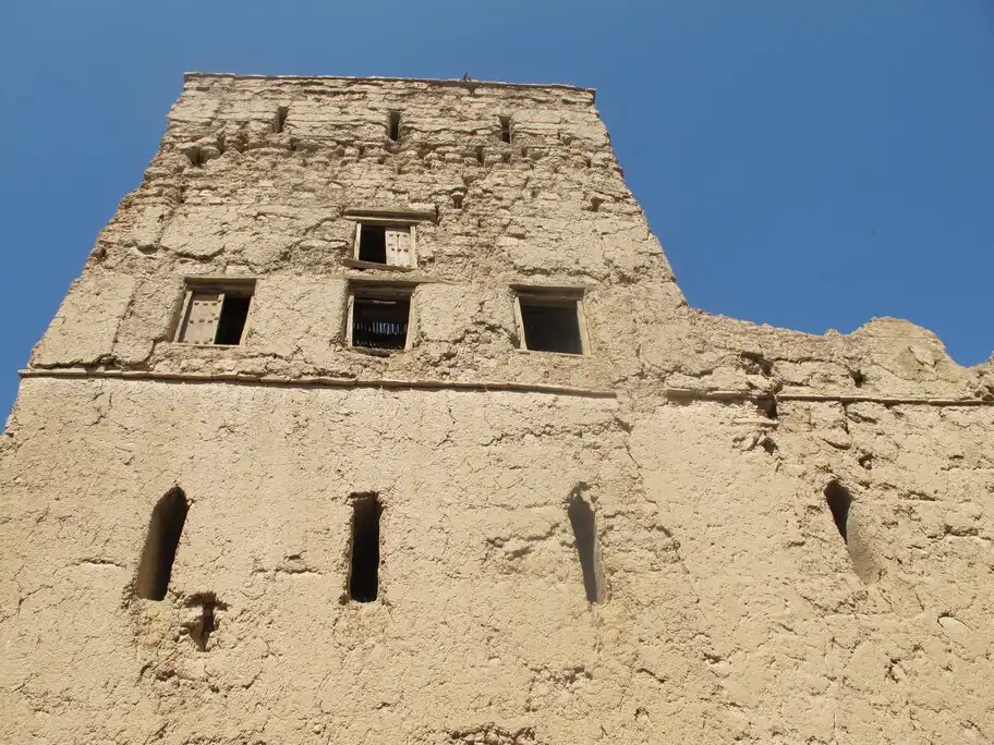 Old mud-brick tower with small windows in the old town of Al Hamra