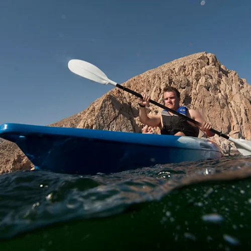 A kayaker paddling below a rocky headland in Musandam