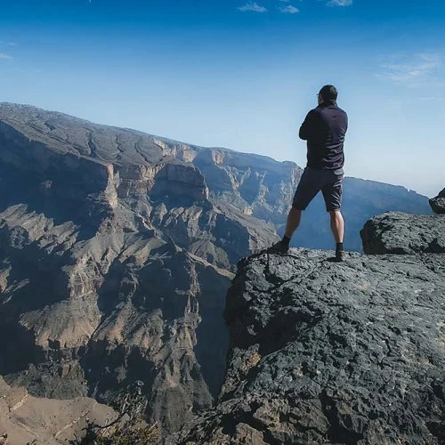 A hiker standing on the rim of the canyon on Jabal Shams