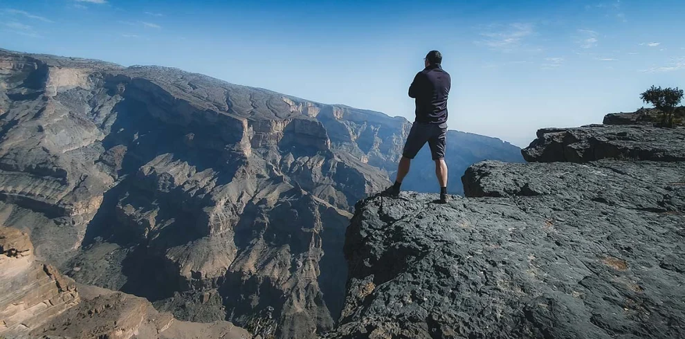 A hiker standing on the rim of the canyon on Jabal Shams