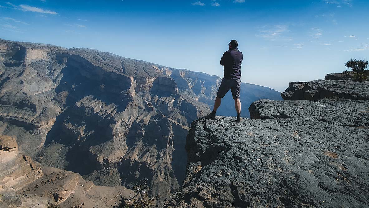 A hiker standing on the rim of the canyon on Jabal Shams