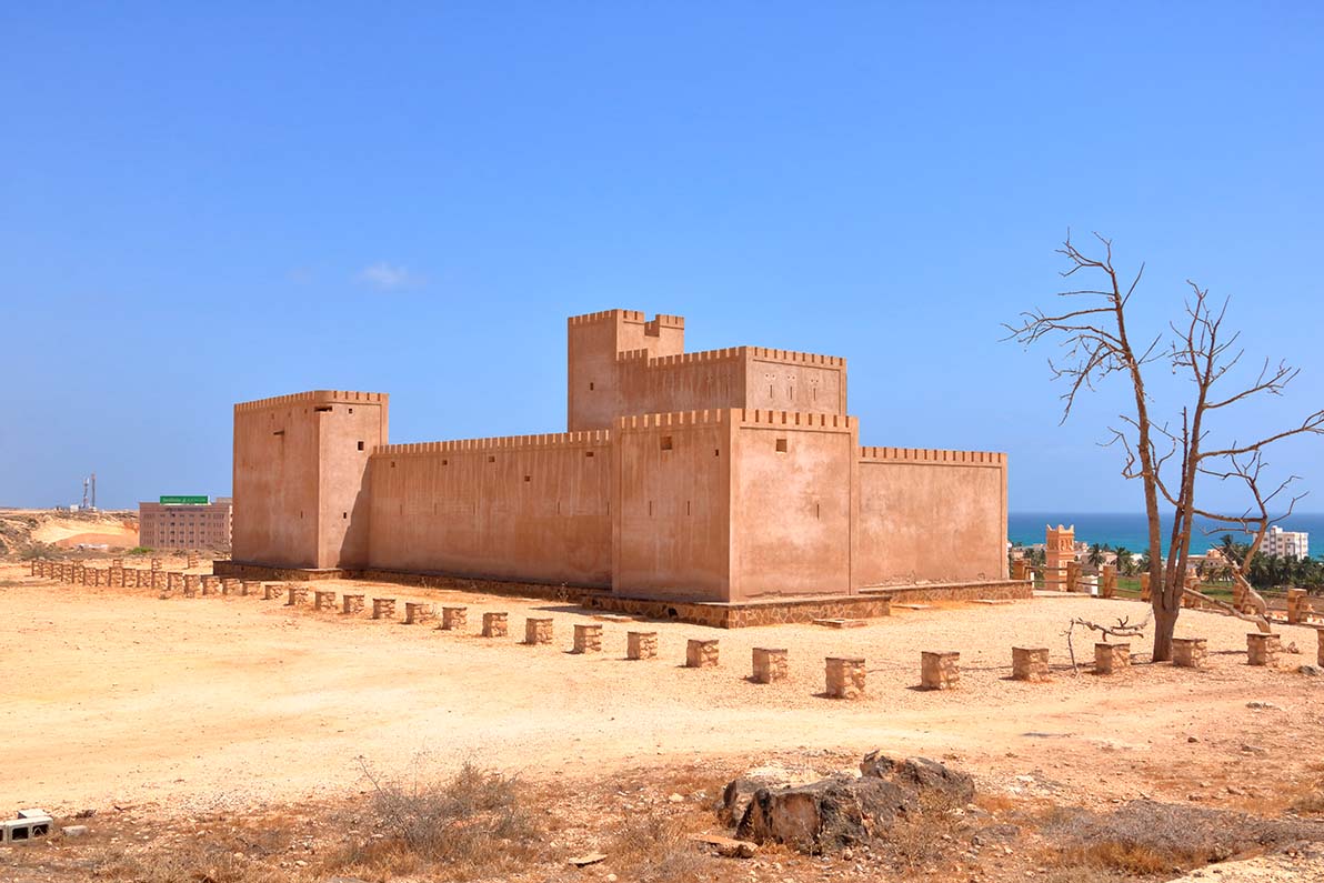 Taqah Castle, a sand-coloured fort under a blue sky