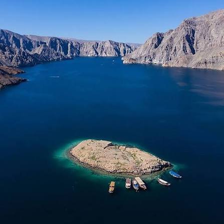 Aerial view of Telegraph Island in a Musandam fjord, with small boats moored