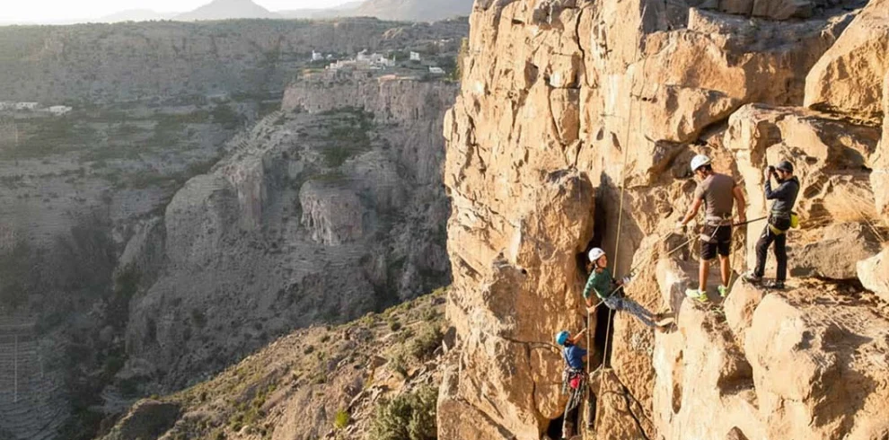 Climbers on a via ferrata on a cliff face above a canyon