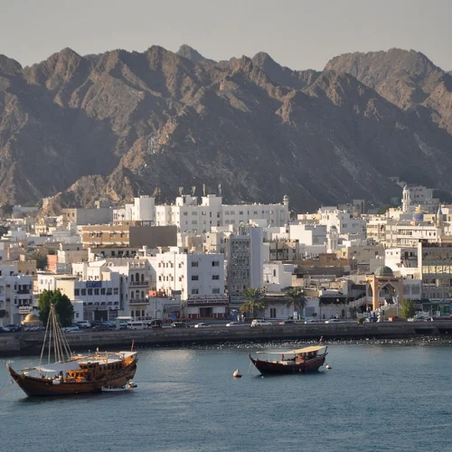 Muscat waterfront with dhows in the harbour and mountains behind