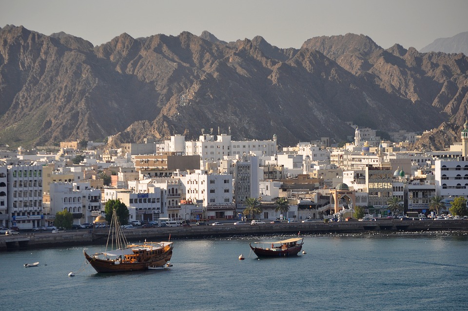 Muscat waterfront with dhows in the harbour and mountains behind
