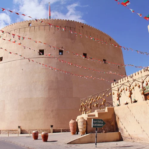 The round tower of Nizwa Fort, with flags strung along the walls