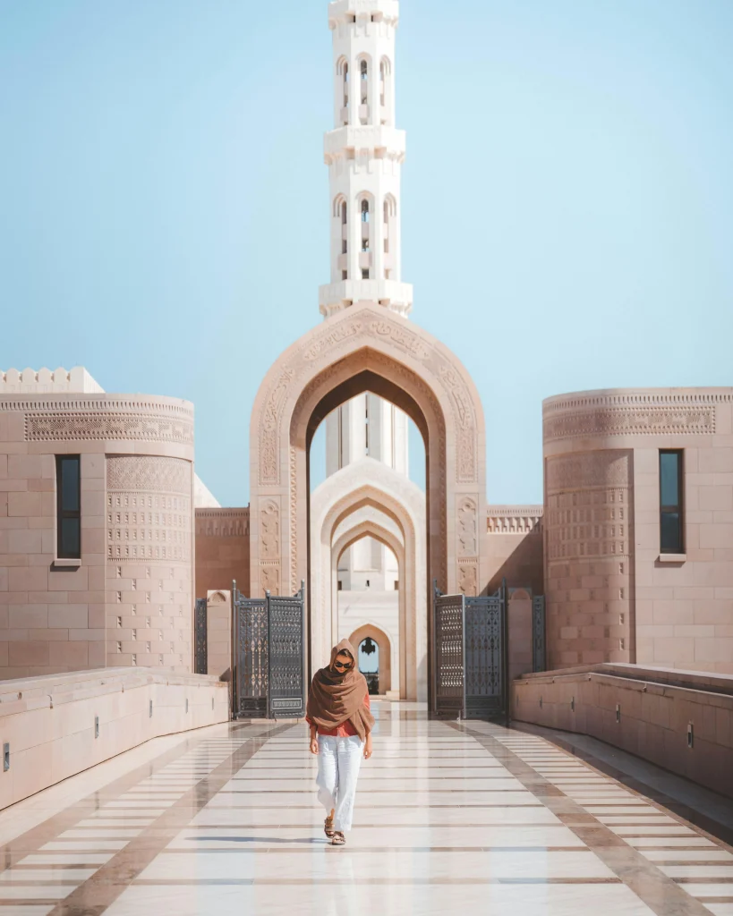 A man walking through an arched gateway at the Sultan Qaboos Grand Mosque