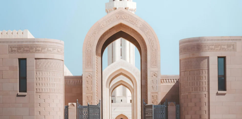A man walking through an arched gateway at the Sultan Qaboos Grand Mosque