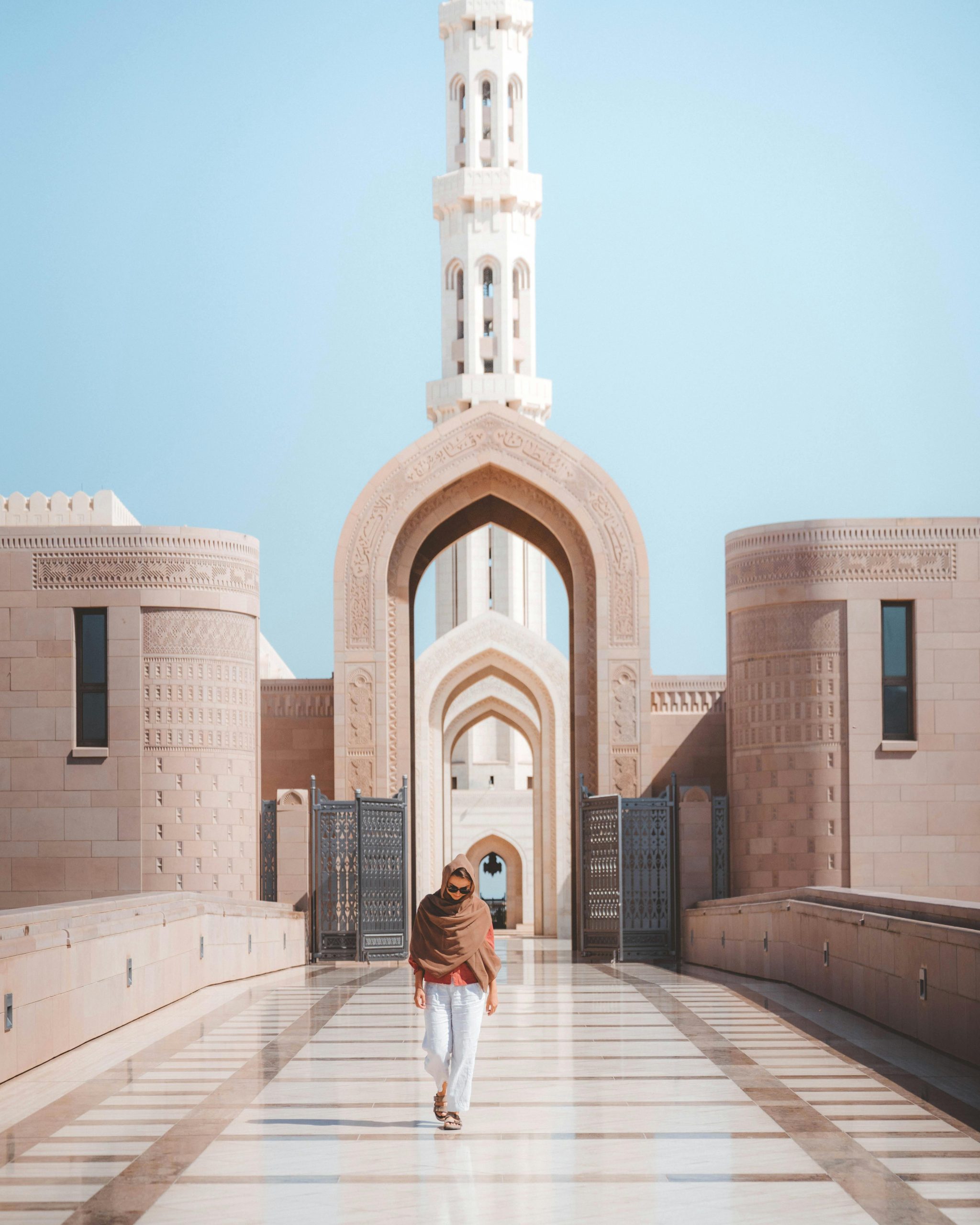 A man walking through an arched gateway at the Sultan Qaboos Grand Mosque